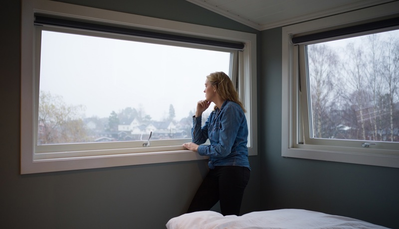 Nainen, joka on joutunut identiteettivarkauden uhriksi katsoo mietteliäästi ulso ikkunasta.